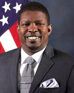 Mr. Dexter Burnam standing in front of a flag.