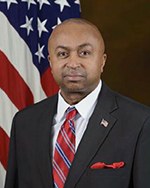 Mr. Howard Ferguson standing in front of a flag.