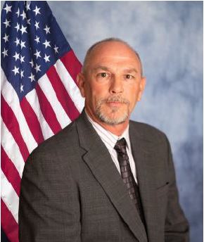 Mr. Rocky Weaver standing in front of a flag.